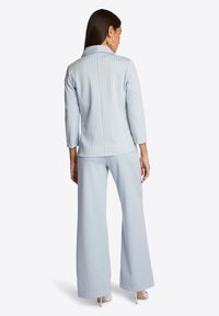 Lichtblauw gestreept shirt met driekwartmouwen, gecombineerd met lichtblauwe wijde broek. Zachte textuur en subtiele glans.