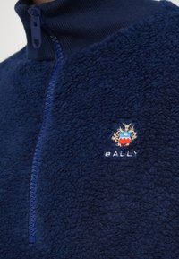 Veste en polaire bleu marine avec tissu texturé, fermeture éclair devant et logo Bally brodé avec un blason sur la poitrine.