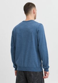 Blauwe trui met een gestructureerd breisel, lange mouwen, ronde hals en ribgebreide zoom. De achterkant toont een standaard pasvorm en een casual ontwerp.