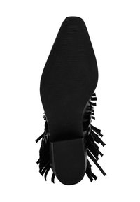 Zapato de tacón negro con punta afilada y suela texturizada. Presenta un detalle de flecos a lo largo de los lados y un acabado elegante y suave.
