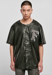 Sort perforeret mesh-jersey med en blank overflade, der fremhæver et iøjnefaldende grå "F" logo og knaplukninger, korte ærmer og detalje med sidetags.