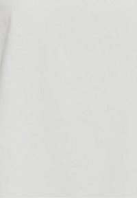 Weißer Leinenstoff mit glatter Struktur, der feine, helle Unregelmäßigkeiten zeigt; gleichmäßige Farbverteilung ohne sichtbare Muster oder Verzierungen.