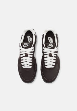 Para czarnych sneakersów Nike z białymi logo Swoosh, białymi sznurowadłami i wyściełanymi kołnierzami, widziana z góry na białym tle.