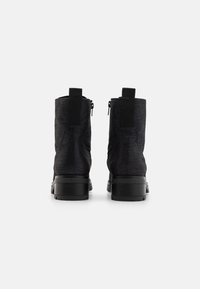 Bottines noires avec une tige texturée, dotées d'une fermeture éclair sur le côté et d'une languette. Semelle en caoutchouc robuste avec un léger talon. Fini lisse.