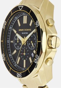 Kuldtooni kroonograaf käekell musta valgega, kontrastsete tunni markeritega ja kuupäeva näidikuga. Omab tugevat korpust ja reguleeritavat metallrandme.