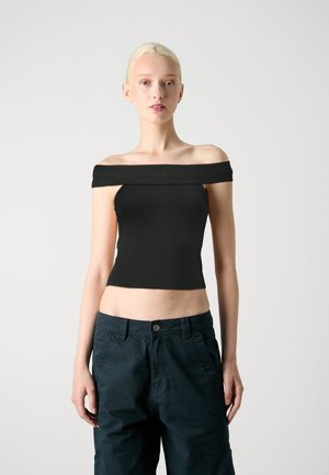 Top nero off-the-shoulder realizzato in tessuto elasticizzato con un design aderente, lunghezza corta e texture liscia. Abbinato a pantaloni cargo blu navy.