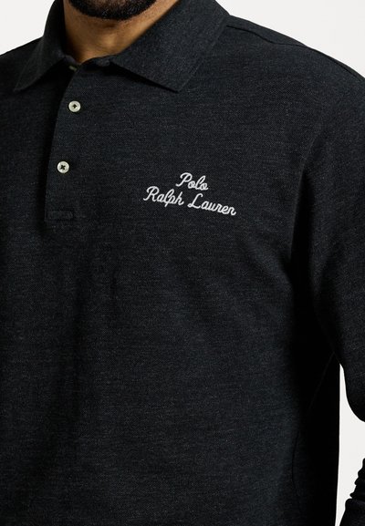 Čierna polo košeľa s textúrovanou tkaninou, dvoma gombíkmi a vyšívaným logom s nápisom "Polo Ralph Lauren" na ľavej strane hrude.