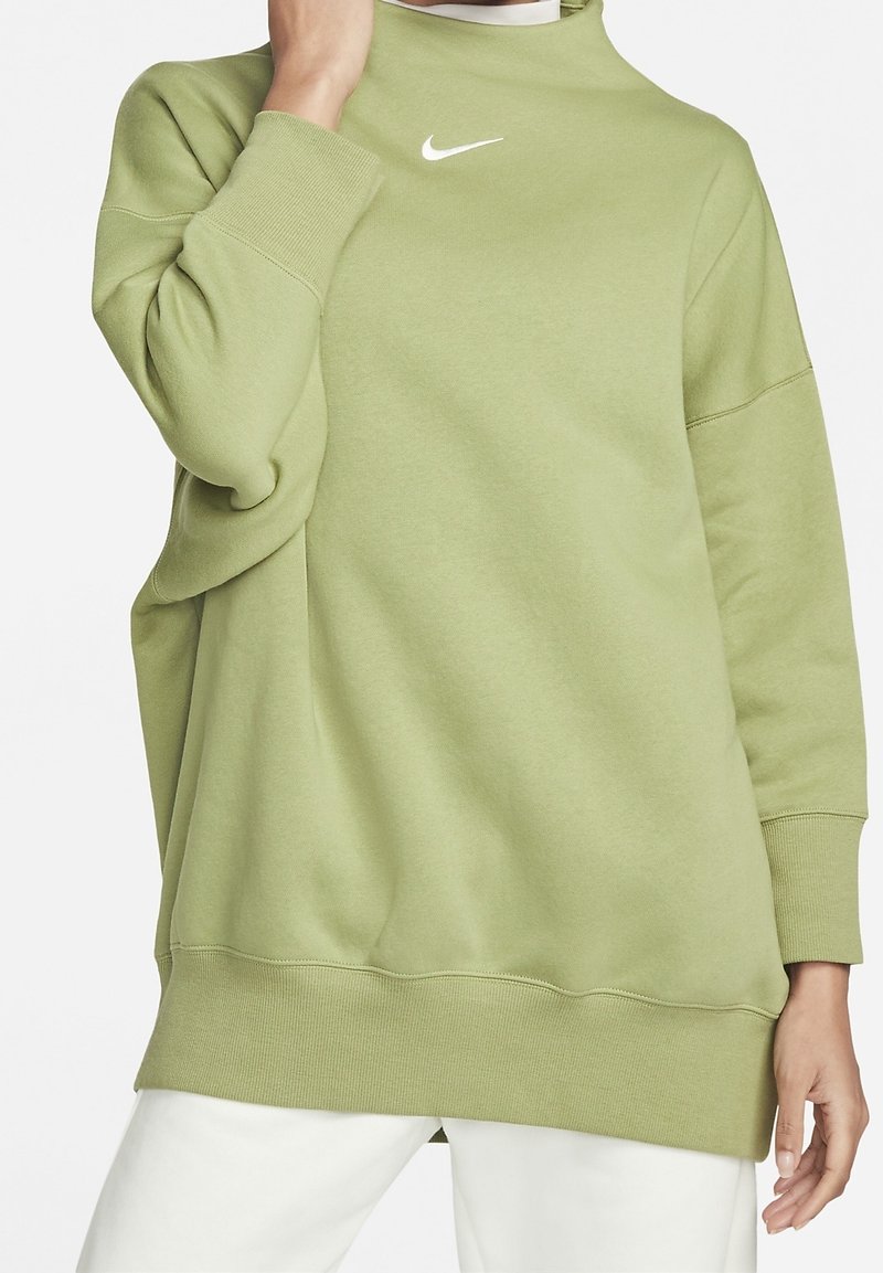 Ljusgrön oversized sweatshirt gjord av mjukt material med hög hals och vit Nike-logotyp på bröstet. Har ribbade ärmslut och nederkant.