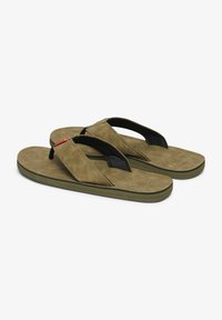 Chanclas de ante marrón con correas de tela negra, suelas planas y plantillas texturizadas. Presentan detalles en acento rojo en la correa.