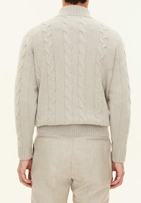 Light gray knitted sweater with cable patterns, high collar, and ribbed hem. Features textured fabric and a cropped design.