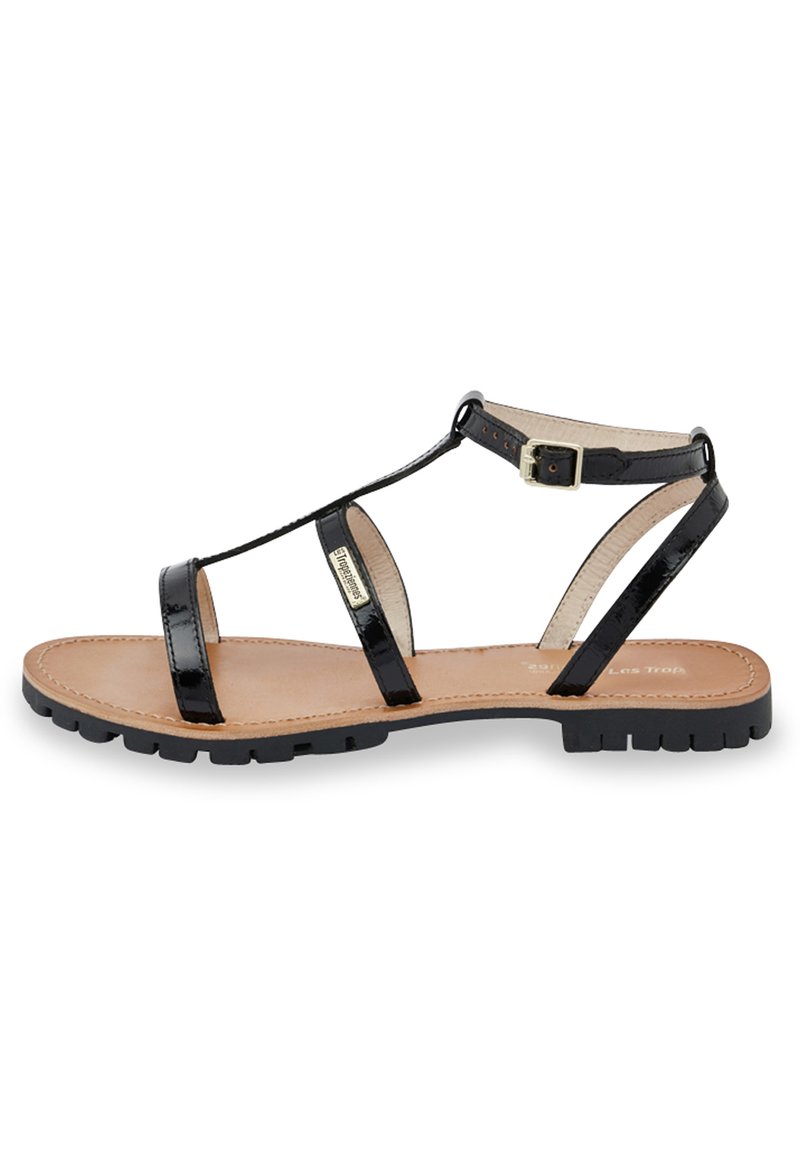 Black patent leather sandals with a T-strap design, adjustable ankle buckle, and a beige cushioned insole on a textured black sole.