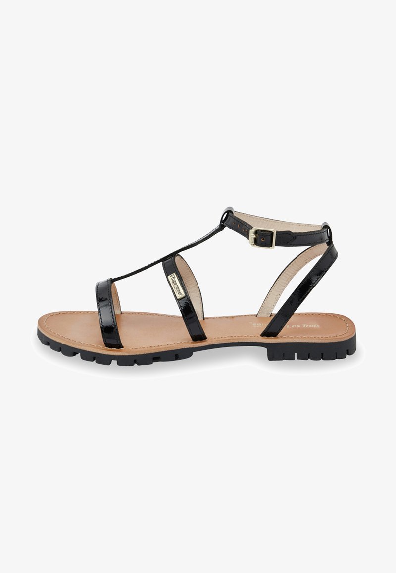 Zwarte lakleren sandalen met een T-band ontwerp, verstelbare enkelgesp en een beige gevoerde inlegzool op een gestructureerde zwarte zool.