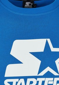 T-shirt in cotone blu con un grande logo grafico bianco con una stella e la parola "STARTER" sul davanti. Collo a coste, maniche corte.