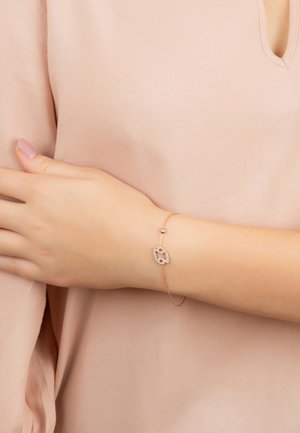 Rose gold bracelet featuring a stylized eye design embellished with clear crystals, connected by a delicate chain.