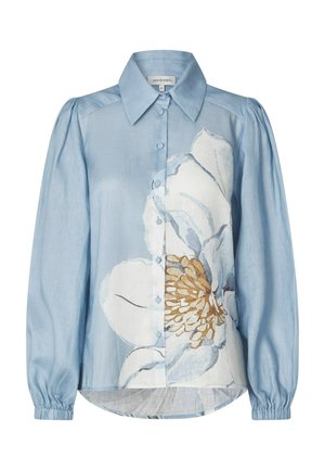 Svetlomodrá blúzka na zapínanie s dlhými nafúknutými rukávmi a veľkým bielo-béžovým kvetinovým vzorom na prednej strane.