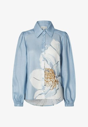 Svetlomodrá blúzka na zapínanie s dlhými nafúknutými rukávmi a veľkým bielo-béžovým kvetinovým vzorom na prednej strane.