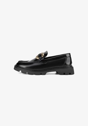 Black patent leather loafers with a chunky rubber sole, featuring a gold-tone decorative hardware detail on the upper.