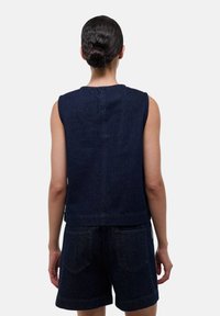 Haut en denim sans manches bleu foncé avec un col rond et une coupe décontractée, associé à un short en denim assorti avec deux poches arrière.