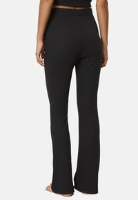 Black flared pants made of stretch fabric, featuring a high waist and smooth texture, with a clean, simple design.