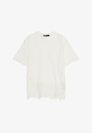 Wit T-shirt met korte mouwen en ronde halslijn, met kantdetail langs de onderzoom, weergegeven tegen een effen witte achtergrond.