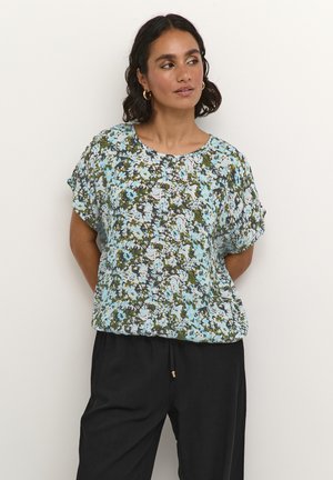 Blouse à manches courtes présentant un motif floral bleu, vert et blanc sur un tissu léger, avec un col rond et une coupe décontractée.