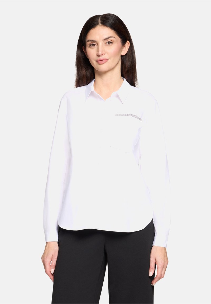 Chemise blanche à boutons avec manches longues, dotée d'une poche poitrine soulignée par un motif subtil et texturé. Tissu lisse, coupe décontractée.