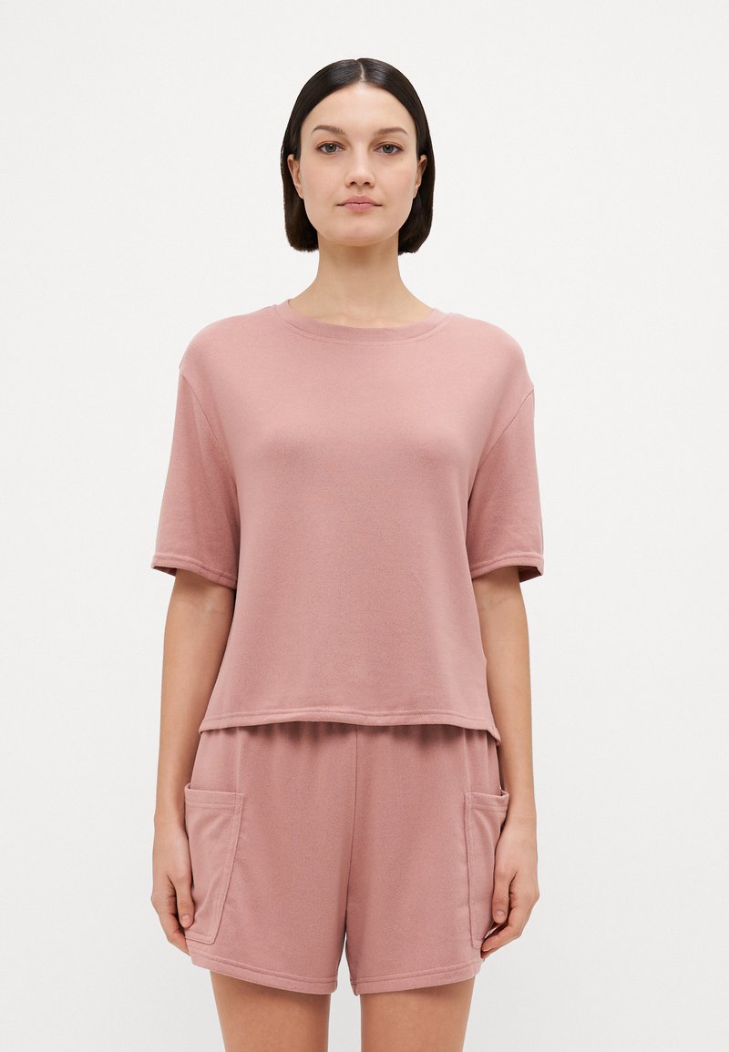 Top rosa a maniche corte con scollatura tonda e vestibilità comoda, abbinato a pantaloni corti coordinati con tasche laterali. Tessuto morbido e testurizzato.