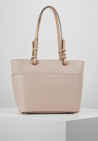 Beżowa skórzana torba na ramię z dwoma regulowanymi paskami, gładką teksturą zewnętrzną i usztywnionym kształtem z płaskim dnem.