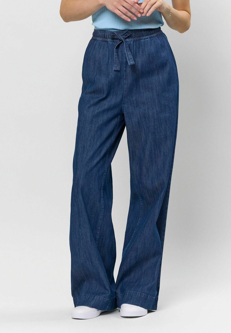 Pantaloni din denim cu picioare largi, de culoare albastru închis, având o talie elastică cu un șnur în față, textură netedă și o croială lejeră.