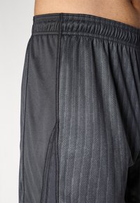 Mustad musta värvi spordilühikesed püksid, mis on valmistatud kergest kangast, milles on tekstuuriline muster, elastne vöökoht ja külgõmblus, et tagada liikumisvabadus.