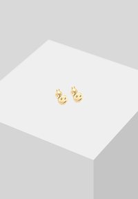 Złote kolczyki w kształcie sztyftów z uśmiechniętą buźką, z detalami twarzy, gładkim wykończeniem oraz zapięciem na motylka.