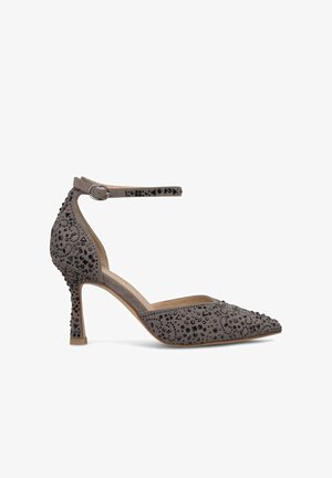 Chaussure à talon en daim gris avec un embout pointu, une bride de cheville et une surface ornée de perles noires géométriques et de détails texturés.