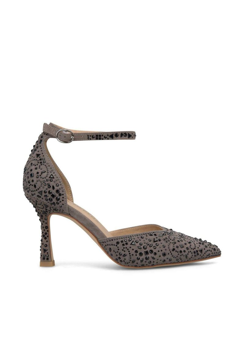 Scarpa con tacco in suede grigio, dalla punta appuntita, con cinturino alla caviglia e superficie decorata da perline nere geometriche e dettagli di texture.