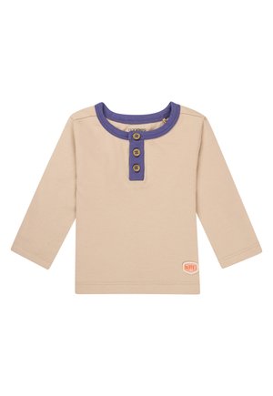 Beige long-sleeve shirt with a purple collar, three button placket, and logo patch on the side. Soft cotton material, casual design.