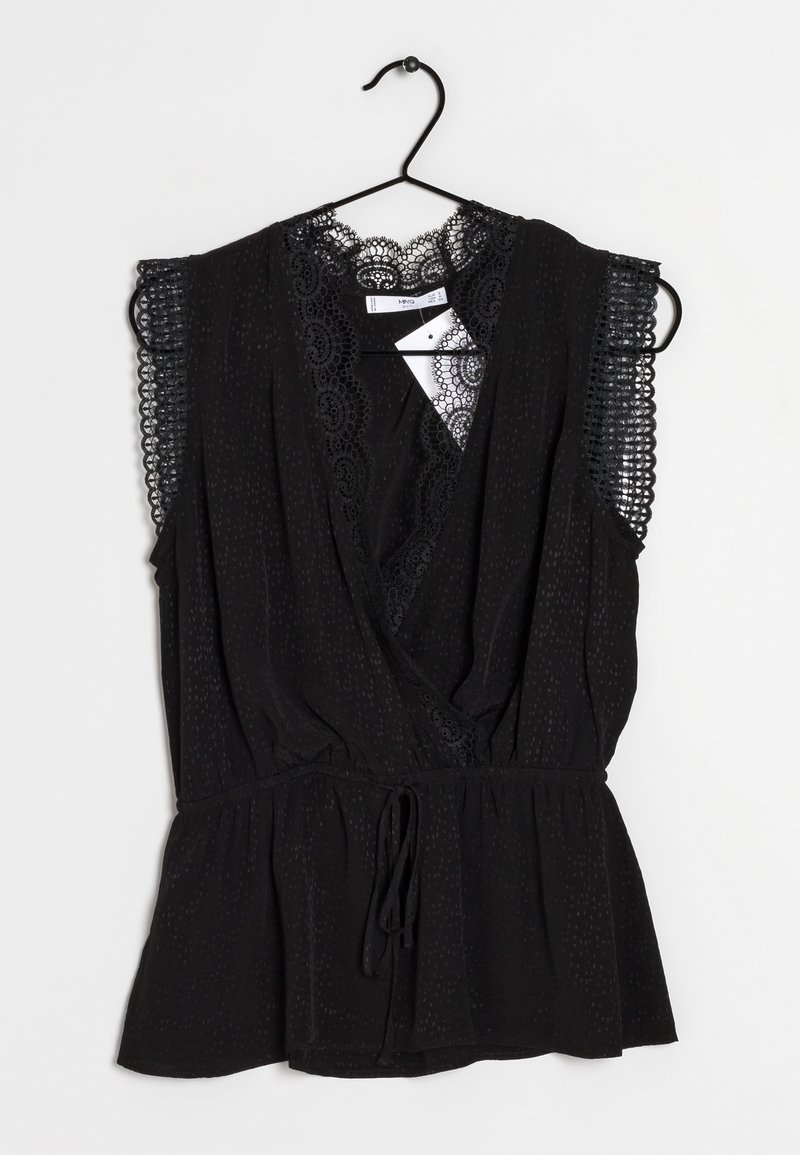 Blouse noire sans manches avec bordure en dentelle aux épaules et à l'encolure, col en V, taille froncée, suspendue sur un cintre noir devant un fond blanc.