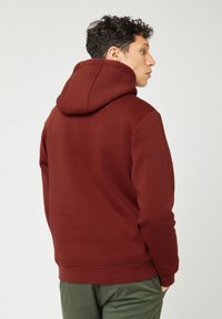 Hoodie in een rijke bordeauxkleur, met een zachte textuur, lange mouwen en een kangoeroezak aan de voorkant.