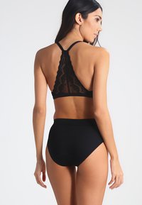 Zwart lingerie set bestaande uit een kant bralette met verstelbare bandjes en high-waisted slips, met een soepele textuur en een aansluitend ontwerp.