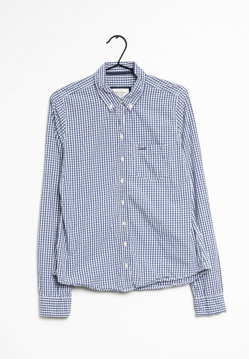 Blue and white checkered long-sleeve shirt with button-down collar, front pocket, and branded patch, made from a textured cotton material.