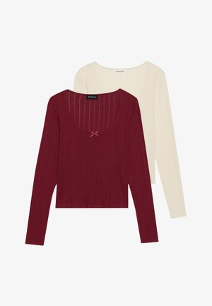 Two long-sleeve tops: one burgundy with ribbed texture and a bow detail at the neckline, and one cream-colored, smooth-textured.