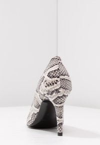 Højhælet sko med spids snude, med et tekstureret sort-hvidt slangeskindsprint og en slank, sort stilethælk.