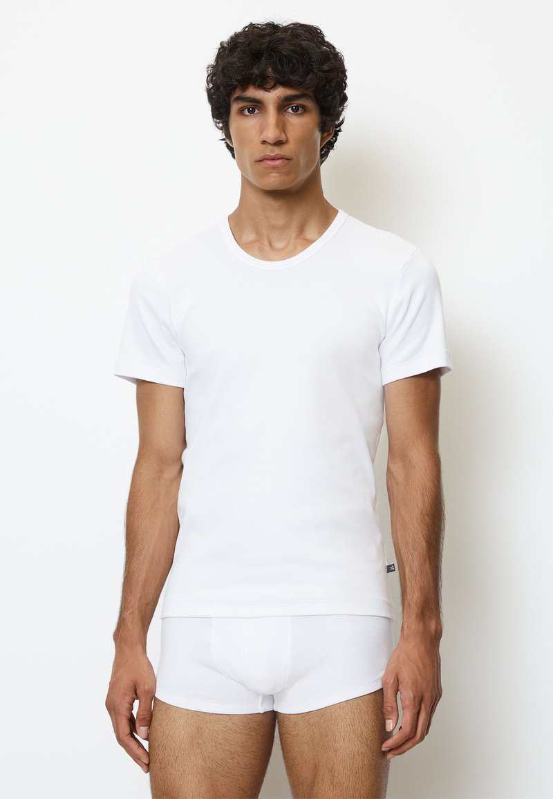 Weiße Kurzarm-T-Shirt und weiße Baumwoll-Shorts. Das T-Shirt hat einen Rundhalsausschnitt und eine glatte Textur.