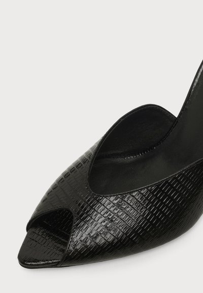 Chaussure à talon haut noire avec texture crocodile, design à bout ouvert et bride arrière sur fond blanc.