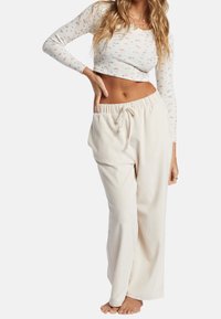 Krämfärgade ribbade byxor med breda ben, elastisk midja och dragsko. Matchas med en figurnära långärmad topp som har ett färgglatt mönster.