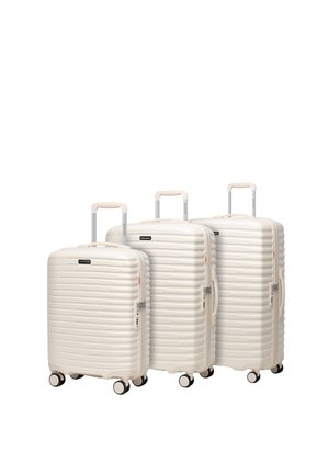 Tres maletas de carcasa dura de color crema de diferentes tamaños, con asas extensibles y cuatro ruedas cada una, dispuestas una junto a la otra.