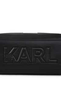 Μαύρη δερμάτινη θήκη με ανάγλυφο το γράμμα "KARL" στο μπροστινό μέρος και μία μικρή μεταλλική πινακίδα λογότυπου στην κορυφή.