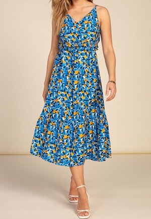 Robe maxi bleue à motif floral avec décolleté en V, fines bretelles et taille volantée. Présente des fleurs jaunes et des feuilles vertes sur fond bleu.