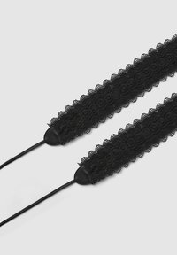 Collana choker in pizzo nero con motivi floreali e bordi scallopati. Presenta estremità in pelle nera e lacci regolabili per una vestibilità sicura.