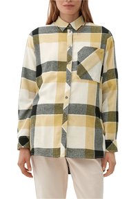 Camicia a quadri realizzata in morbido cotone, con quadrati gialli, verdi, grigi e neri. Include una tasca e un colletto con bottoni.