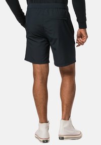Svarta shorts med elastiskt midjeband och en bakficka. Tillverkade i ett mjukt tyg, knälång design, kombinerade med vita högskor.