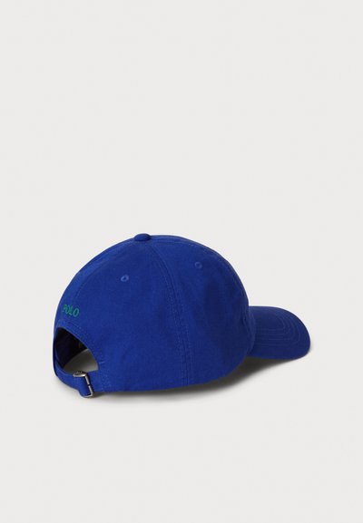 Μπλε βαμβακερό καπέλο μπάσκετ με ρυθμιζόμενο λουράκι, με πράσινο κεντημένο λογότυπο στο πίσω μέρος και καμπύλη γείσο. Λεια υφή, κλασικός σχεδιασμός.